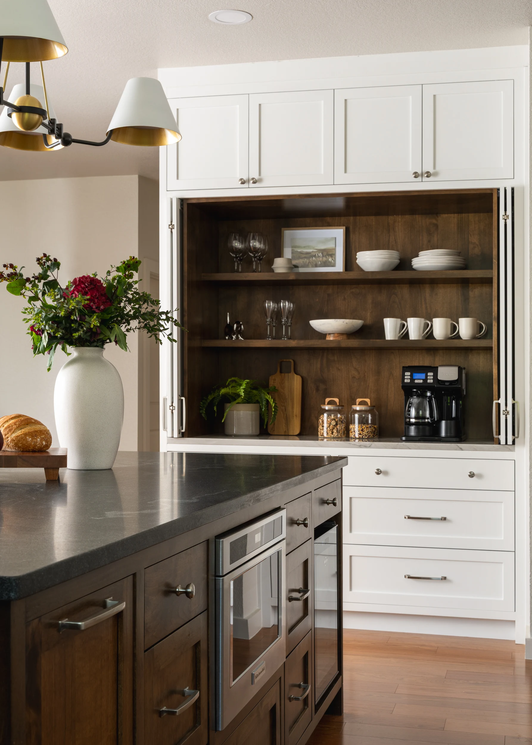 Flowers and bread on the dark island, with the walnut hutch open behind