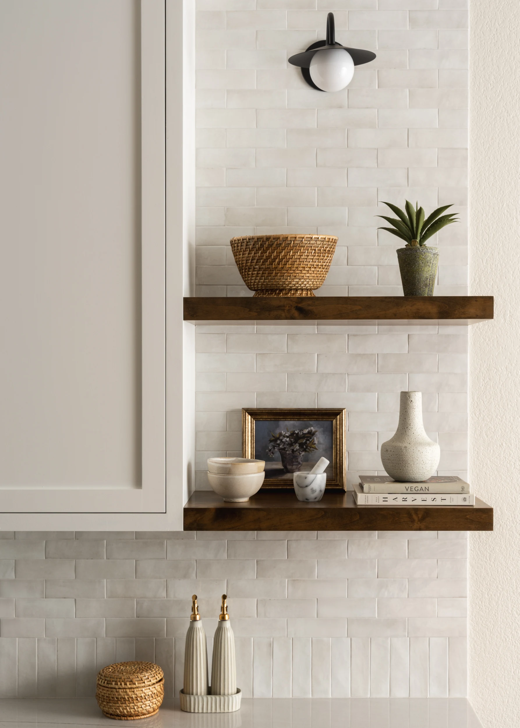 Walnut floating shelves styled with a basket and a plant against white tile