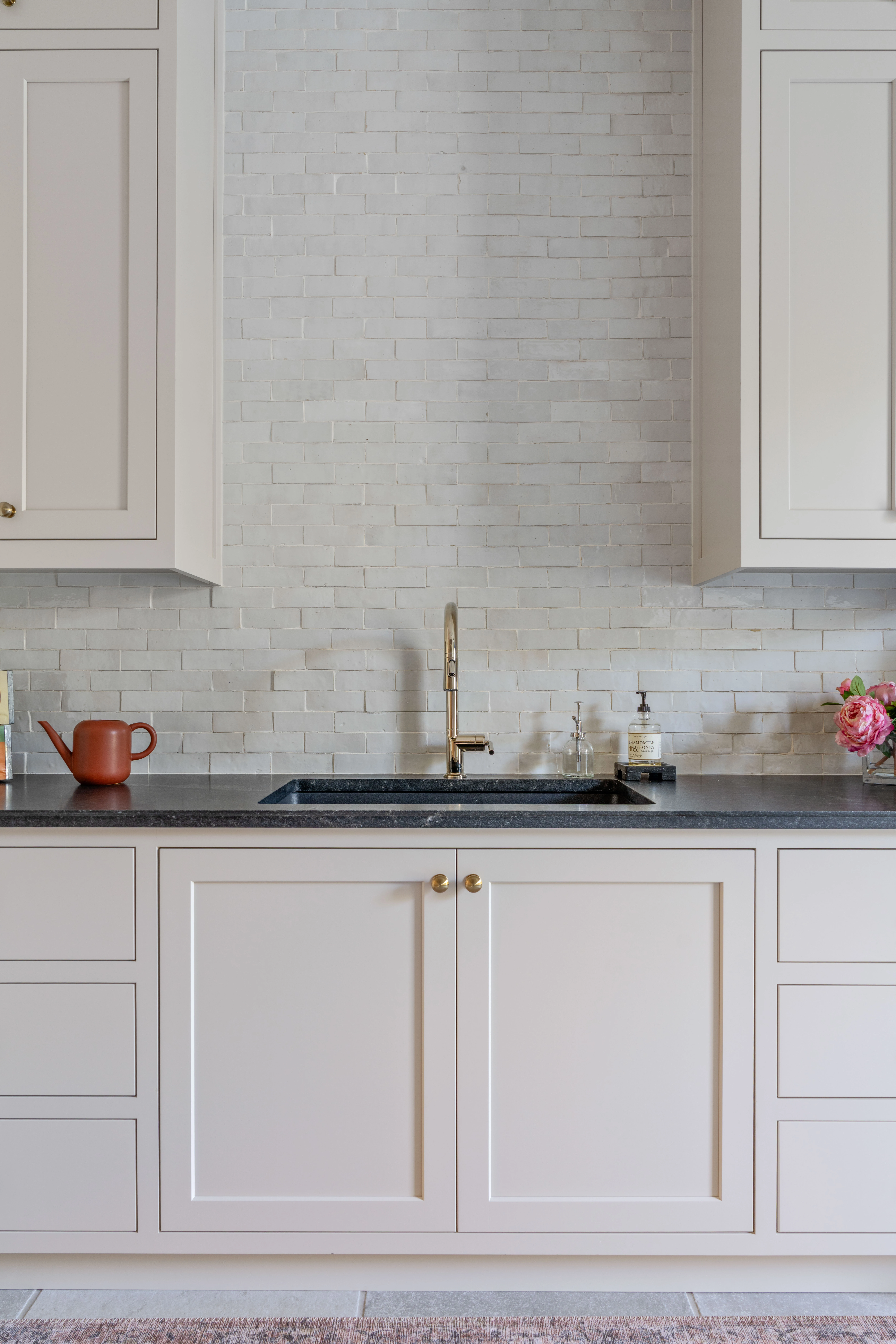 Butler's pantry sink set into a dark stone counter with a brass tap