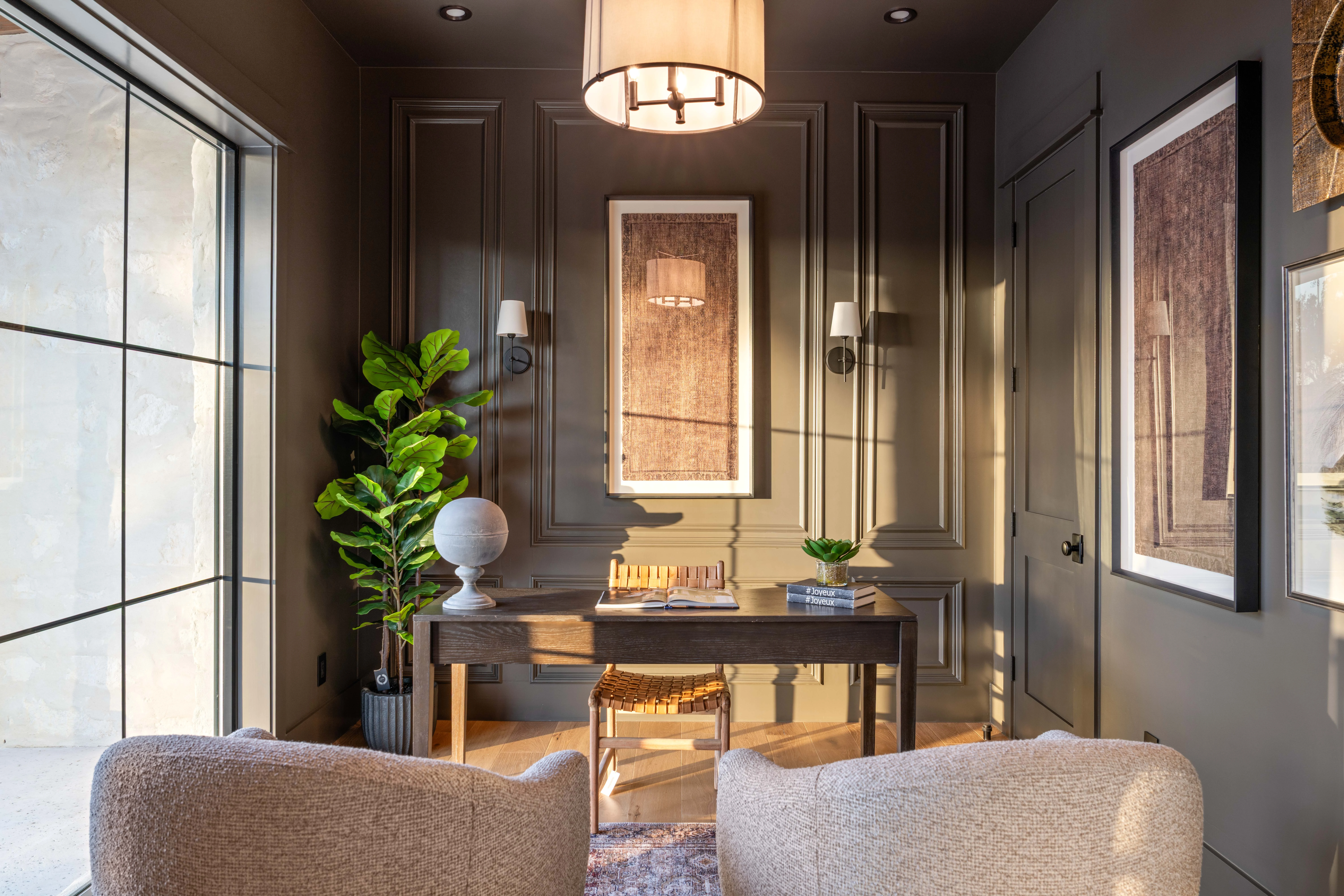 Panelled study with a timber desk, boucle armchairs and framed art