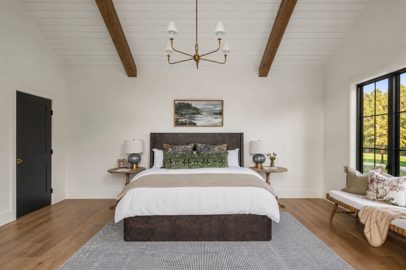 Primary bedroom under a vaulted plank ceiling with exposed beams