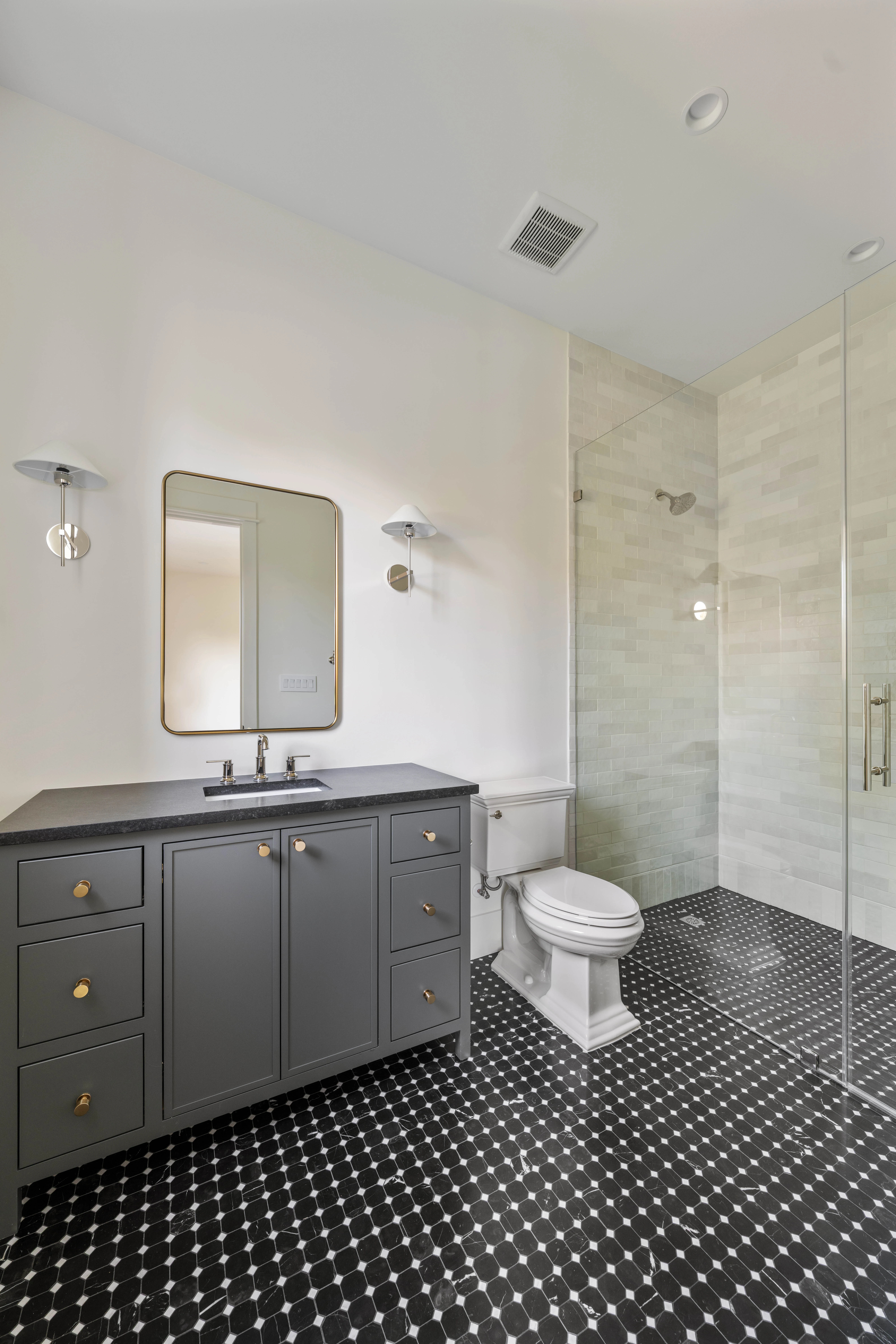 The charcoal vanity seen across the black and white tile floor