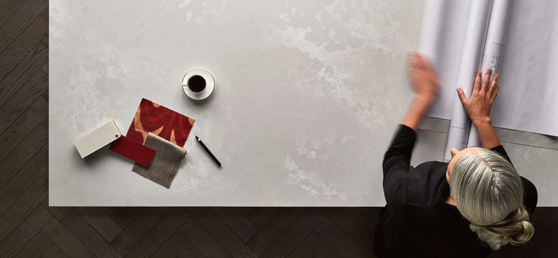 Overhead view of a pale Caesarstone Cloudburst Concrete surface laid with fabric samples and a coffee
