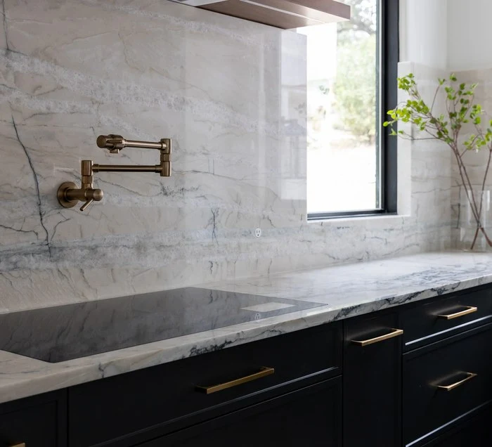 Gold bridge faucet against a Fantasy Lux quartzite backsplash