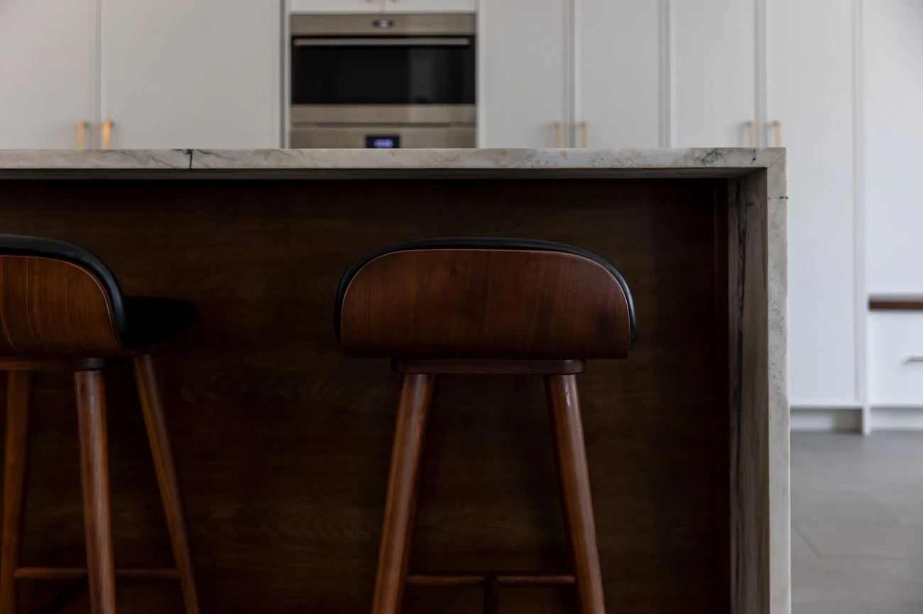 Walnut and black counter stools at the island, dark cabinetry behind