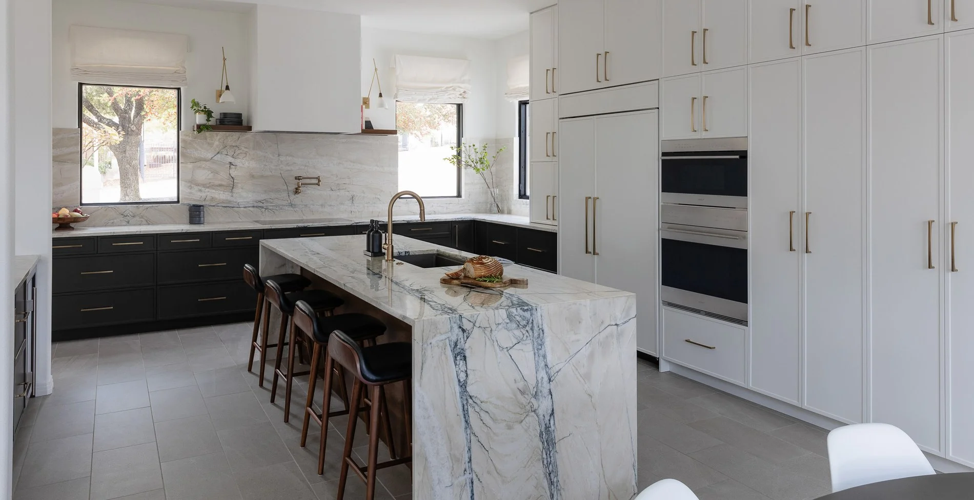 Fantasy Lux quartzite waterfall island with walnut counter stools in a white and black Austin kitchen
