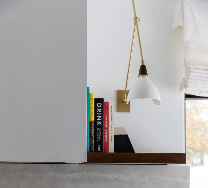 Walnut open shelf with cookbooks beside a pendant light