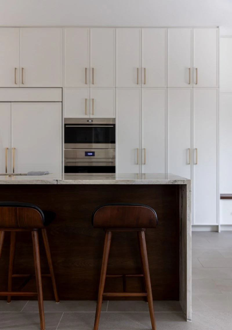 Walnut counter stools at the wet bar beneath white cabinetry