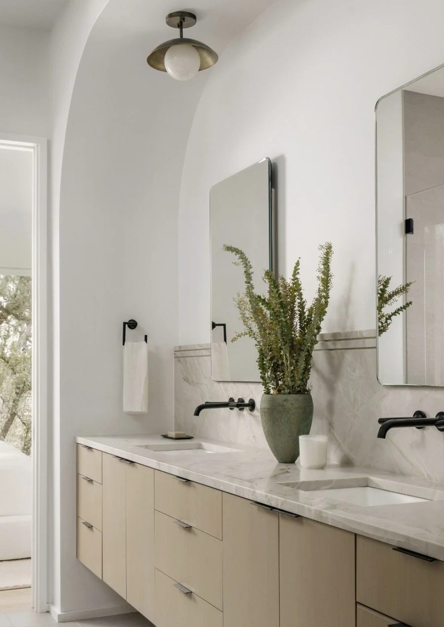 Double vanity beneath arched alcoves with a stone countertop