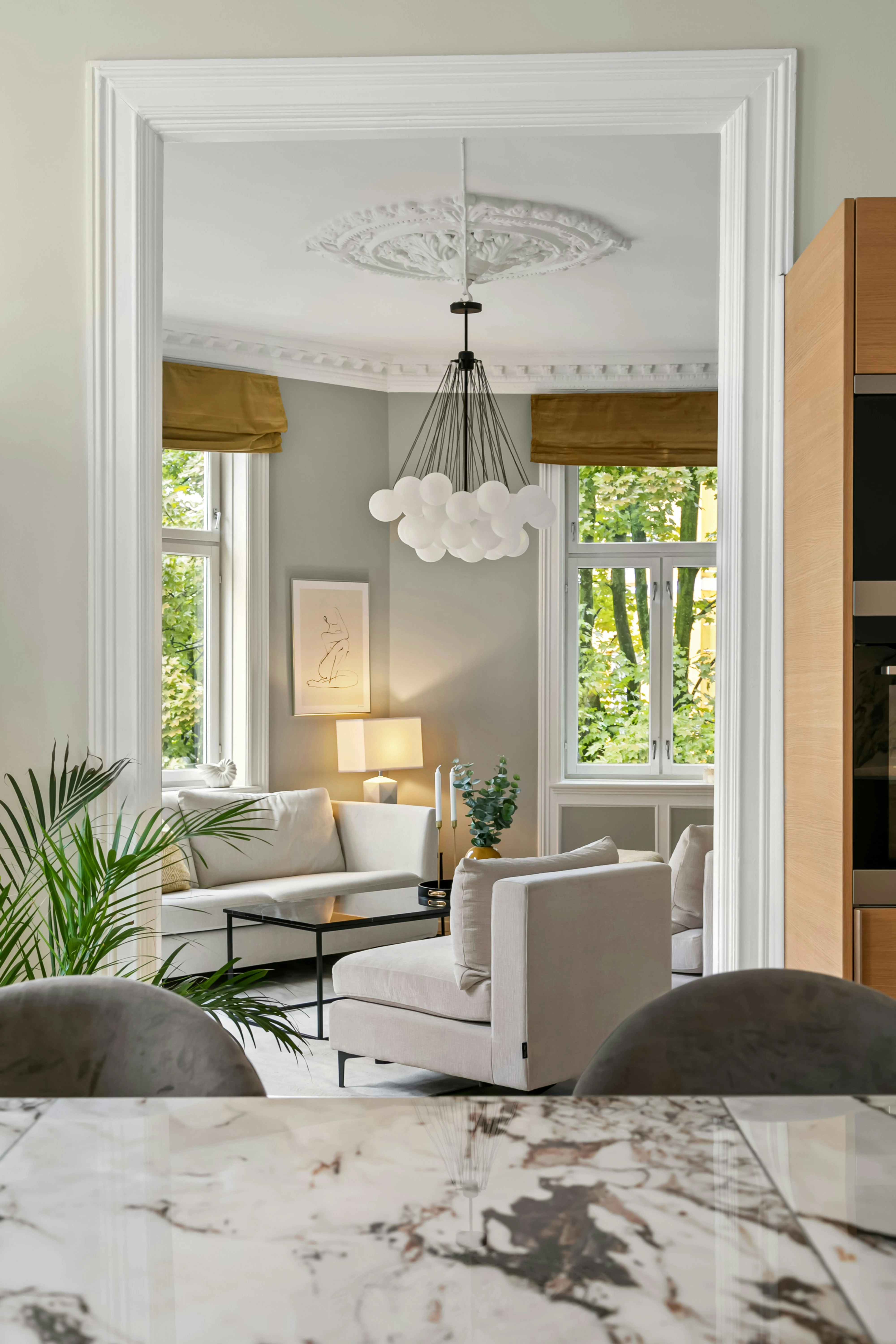Living room seen through a doorway, beyond a white marble counter with grey veining