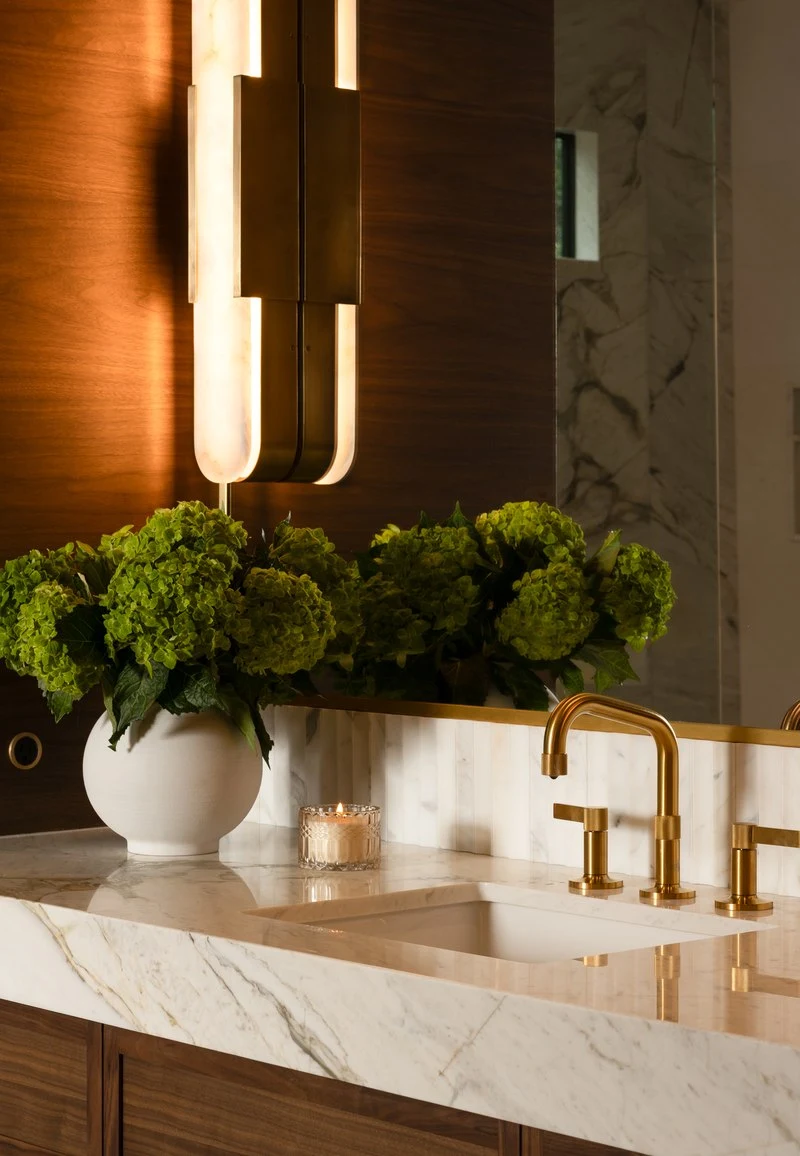 Marble vanity with a brass faucet and hydrangeas