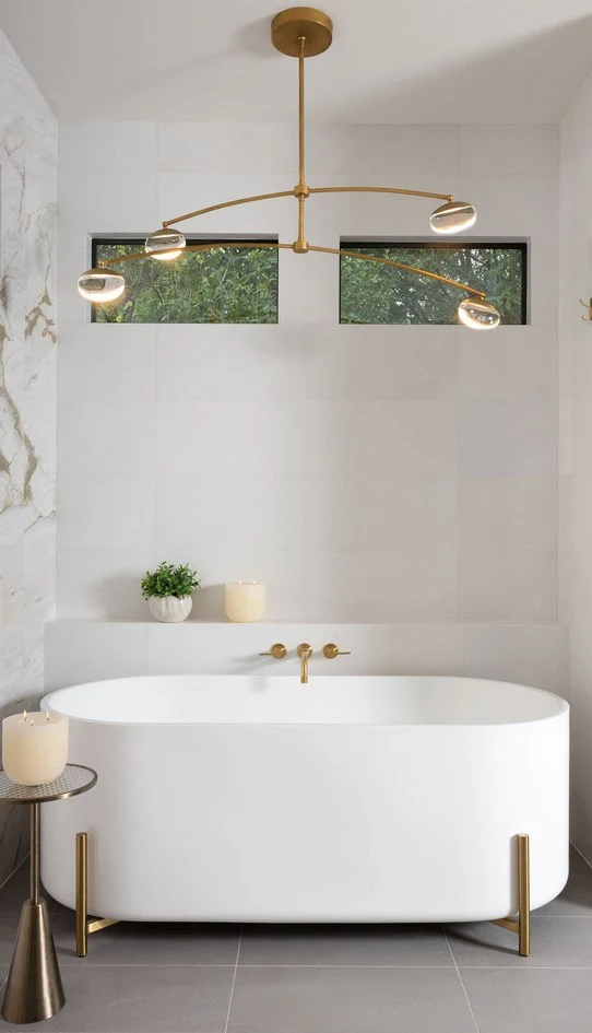 Freestanding tub under a brass chandelier in the primary bath