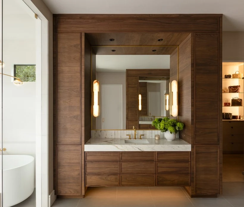 Walnut double vanity framed in a mirrored alcove