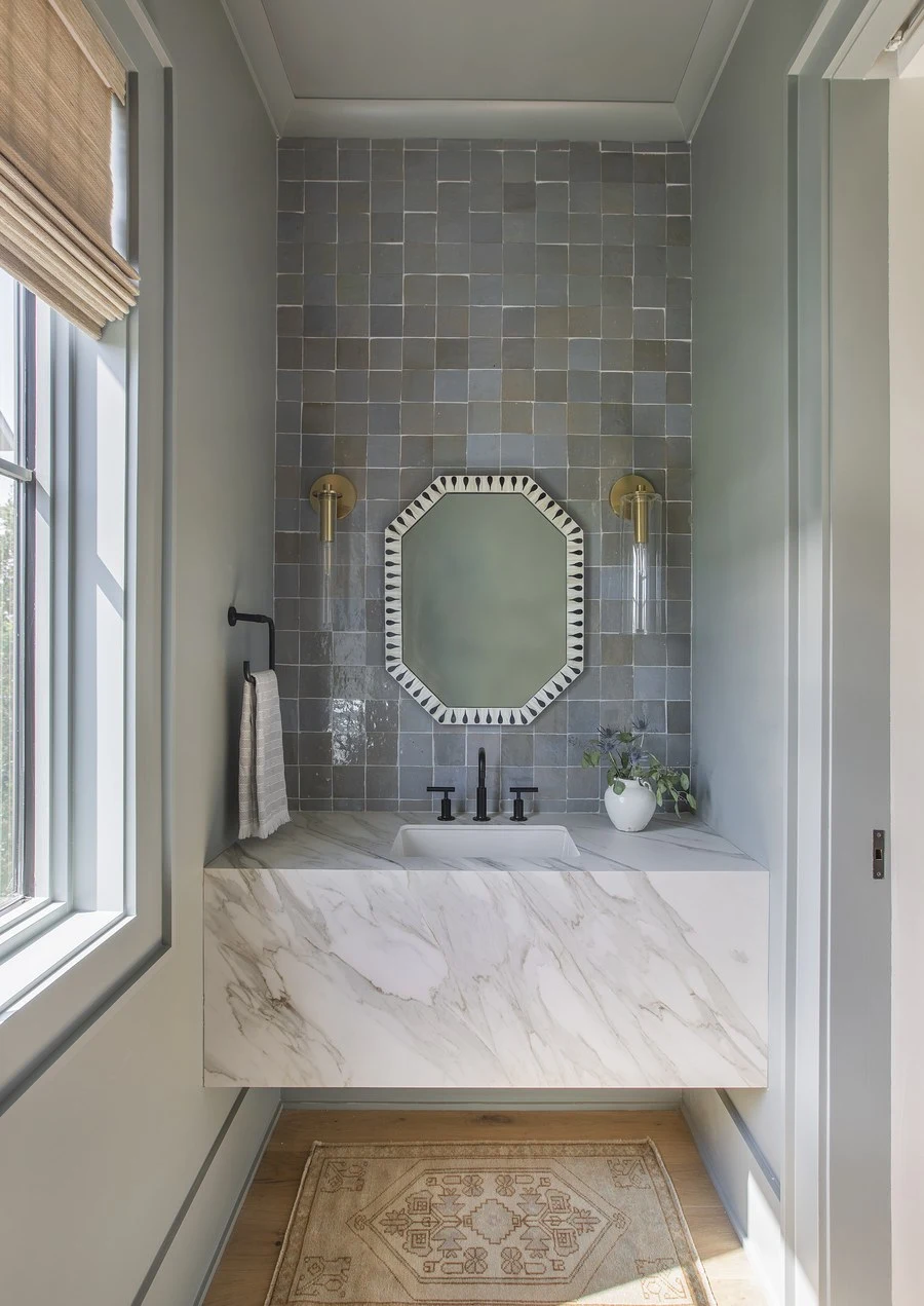 Powder room with herringbone tile and a marble pedestal basin