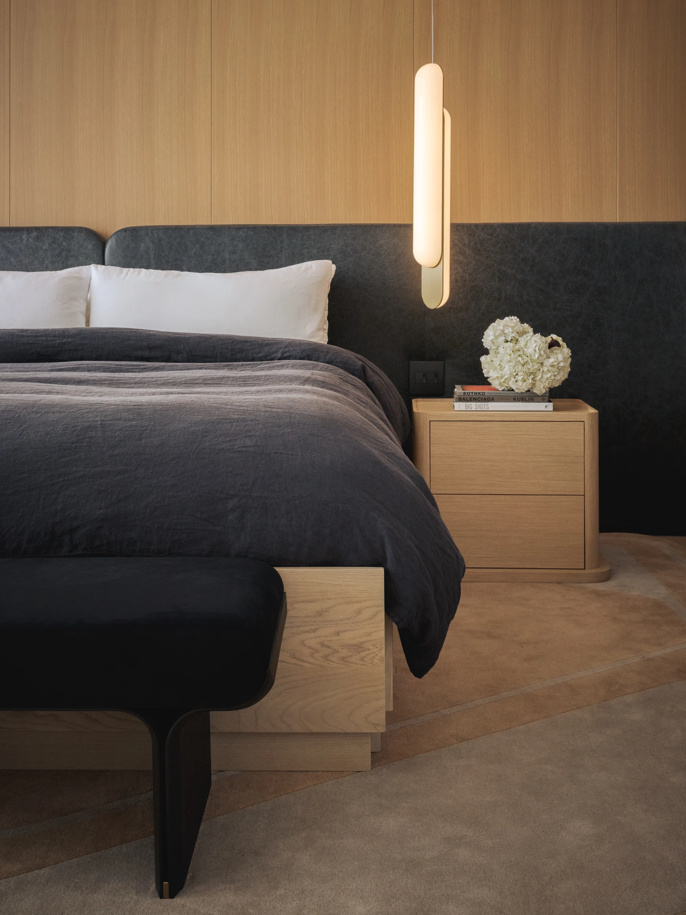 Oak bed with a charcoal headboard and a slim pendant over the nightstand