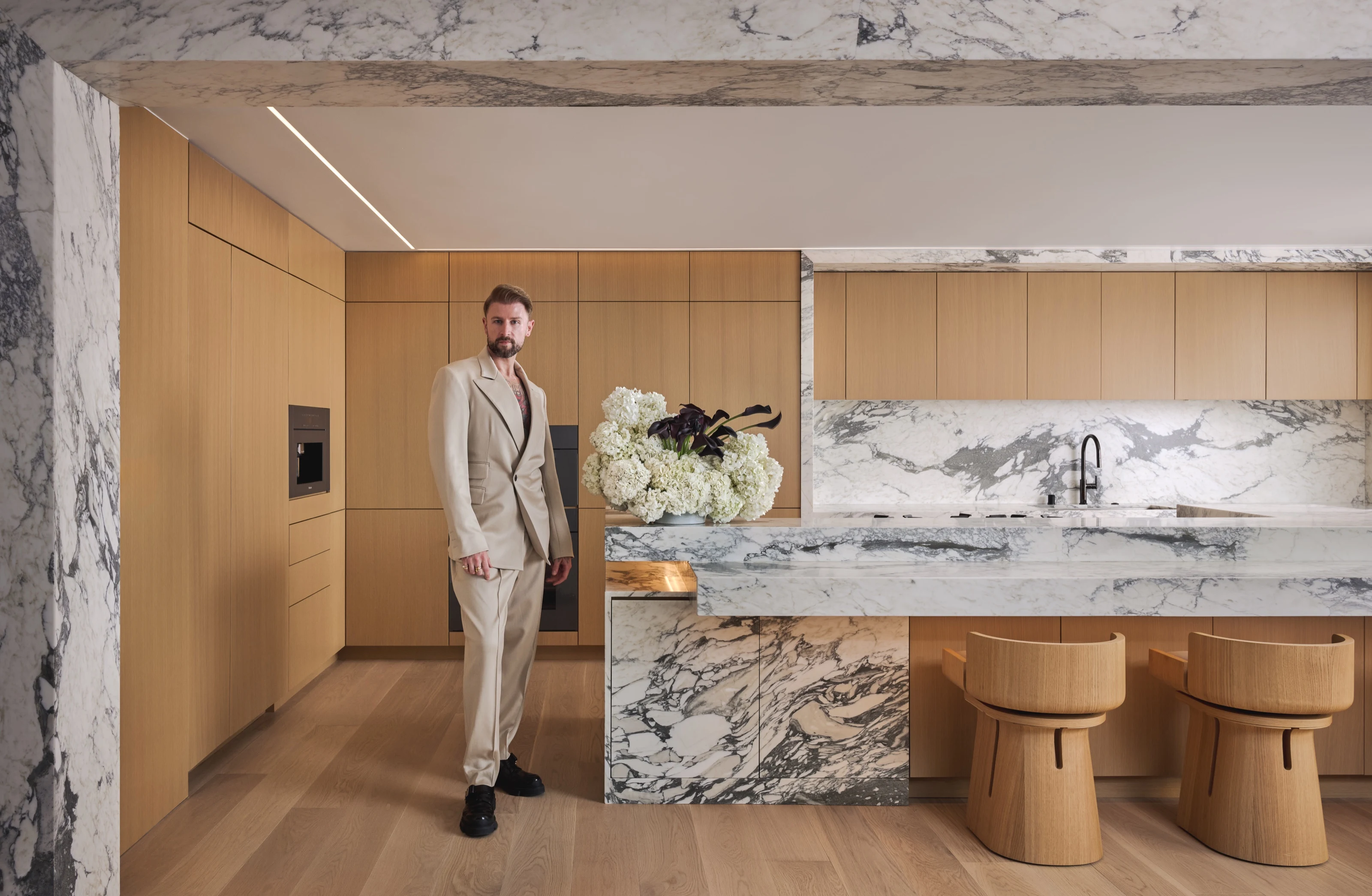 Phoenix Grey standing beside the marble kitchen island with a bouquet of hydrangeas