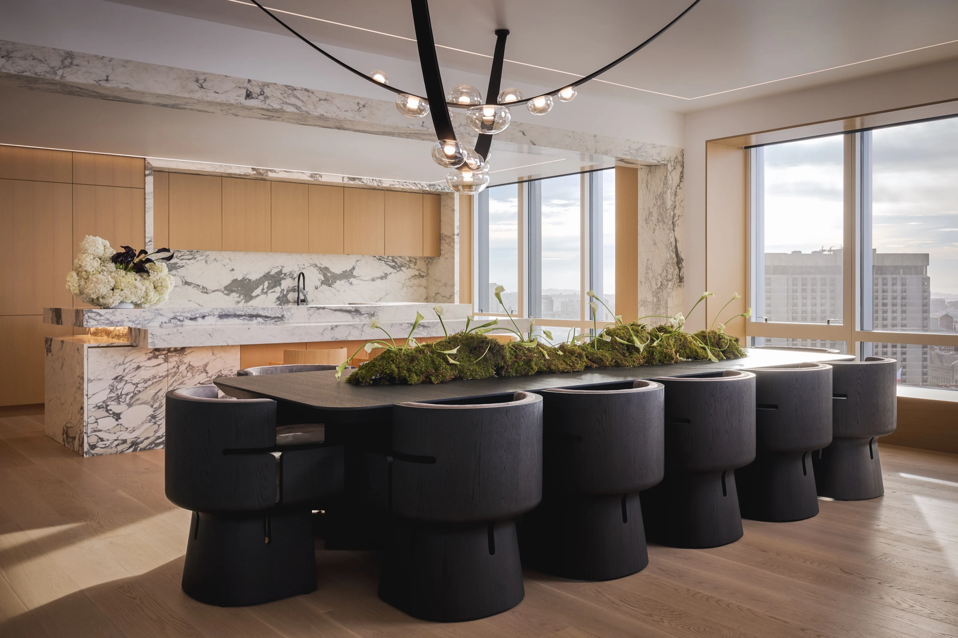 Black dining chairs around a table planted with a moss centerpiece