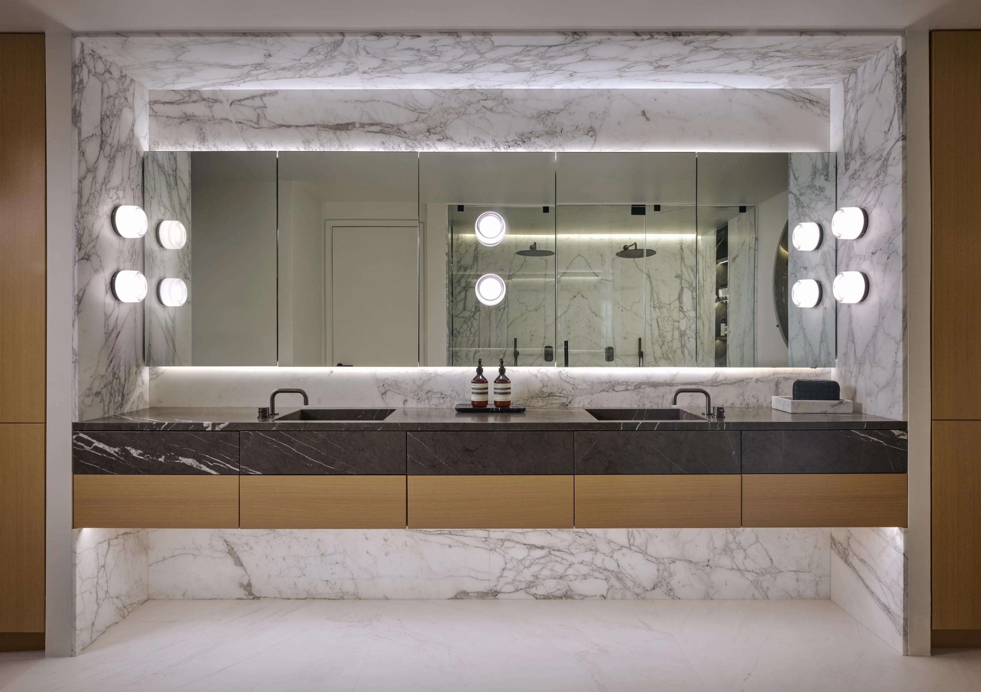 Double vanity with globe sconces against a book-matched marble wall