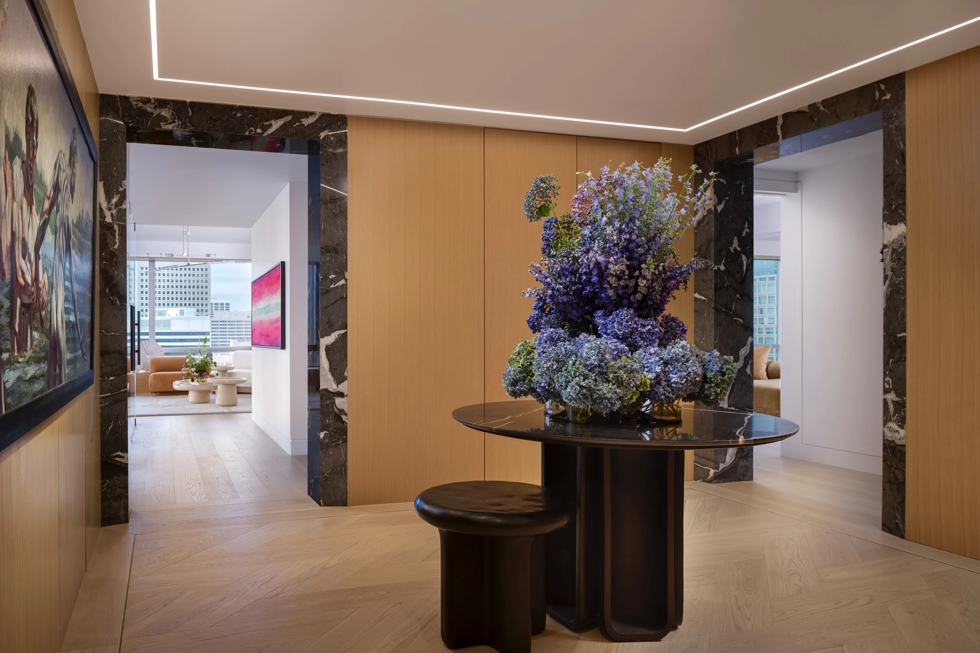 Foyer with a round pedestal table of blue hydrangeas between dark marble portals