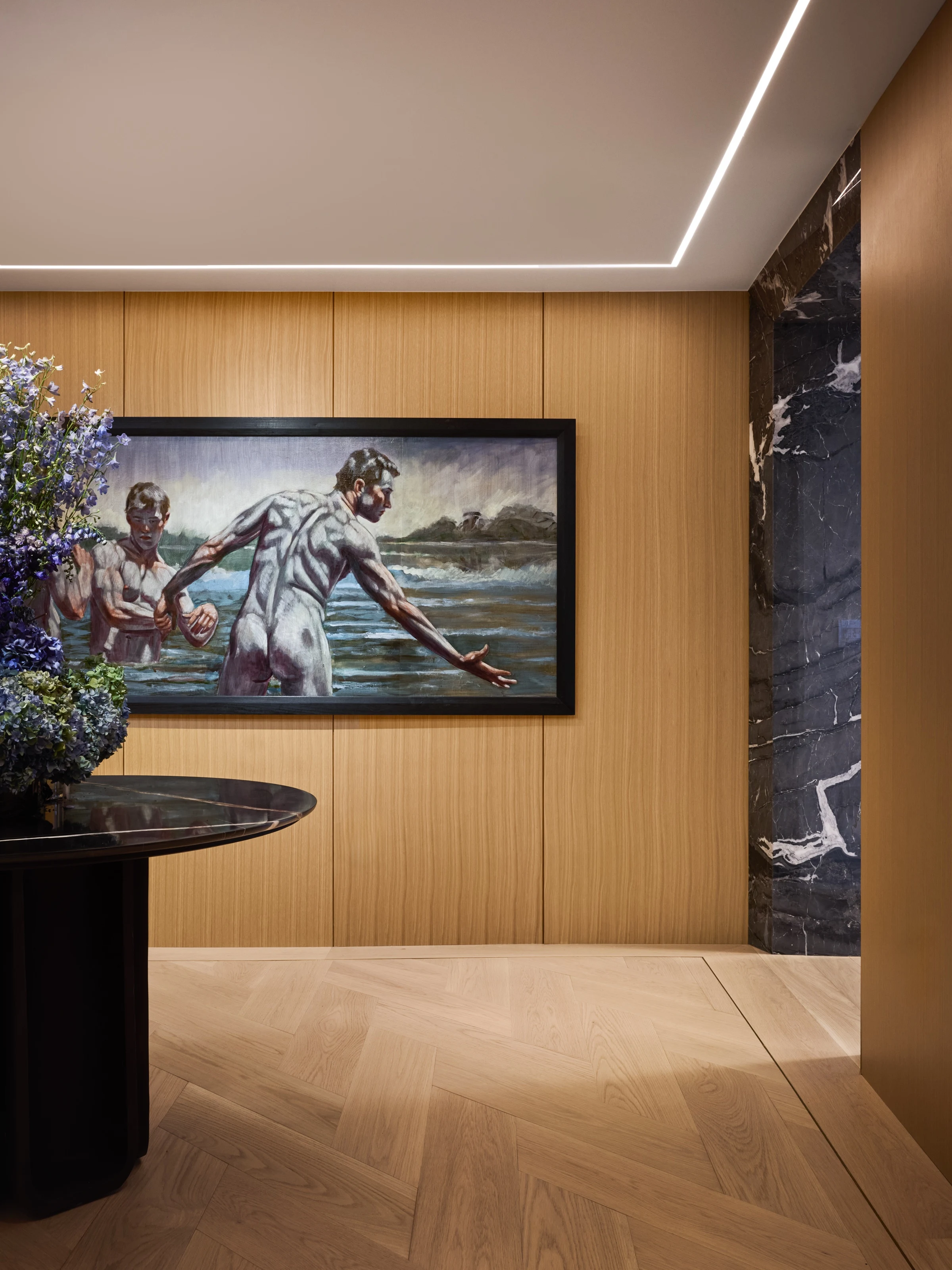 Oak-paneled hallway framed by a dark veined marble portal, a painting on the wall beyond