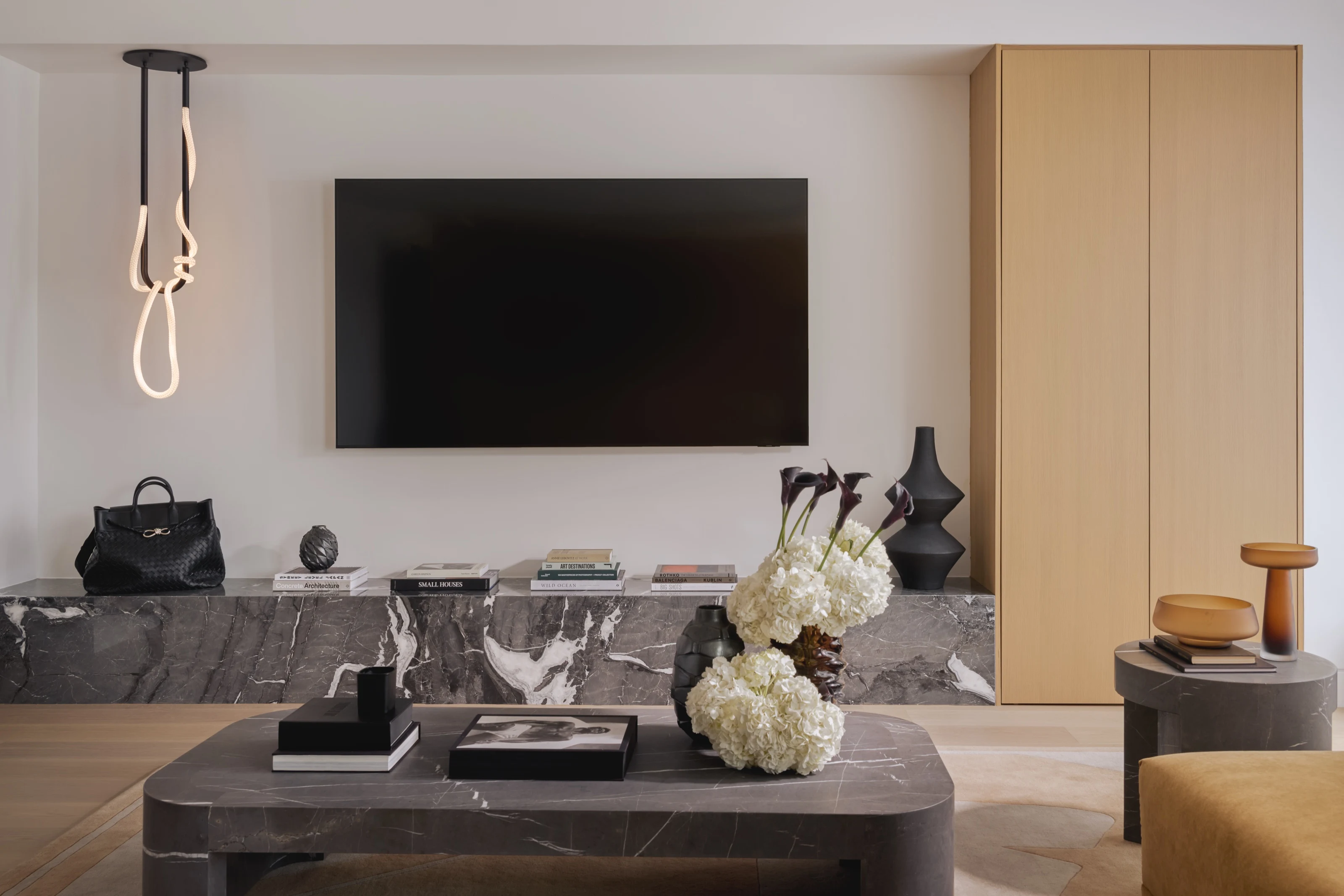 Dark marble media console and coffee table beneath a wall-mounted screen