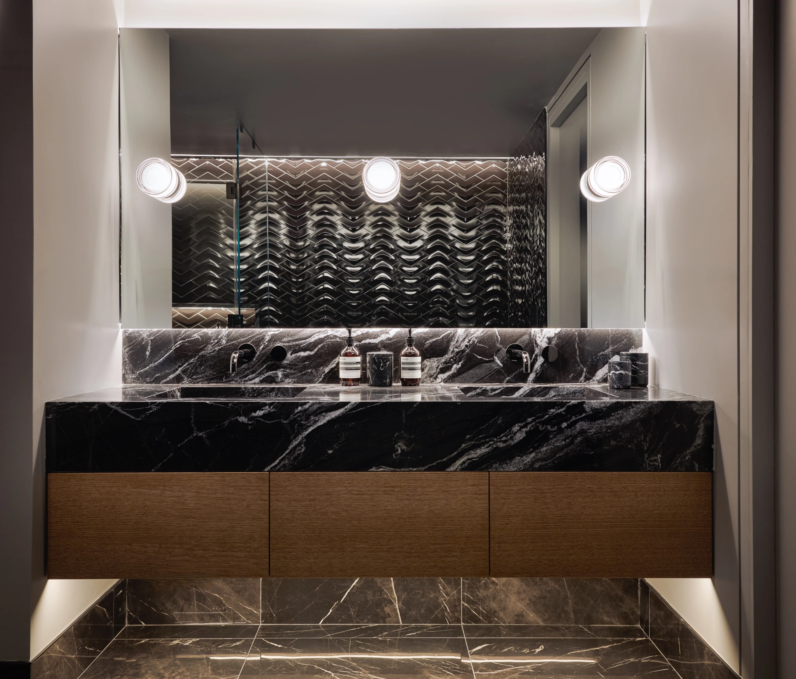 Oscuro Mist granite vanity on oak drawers beneath a backlit mirror