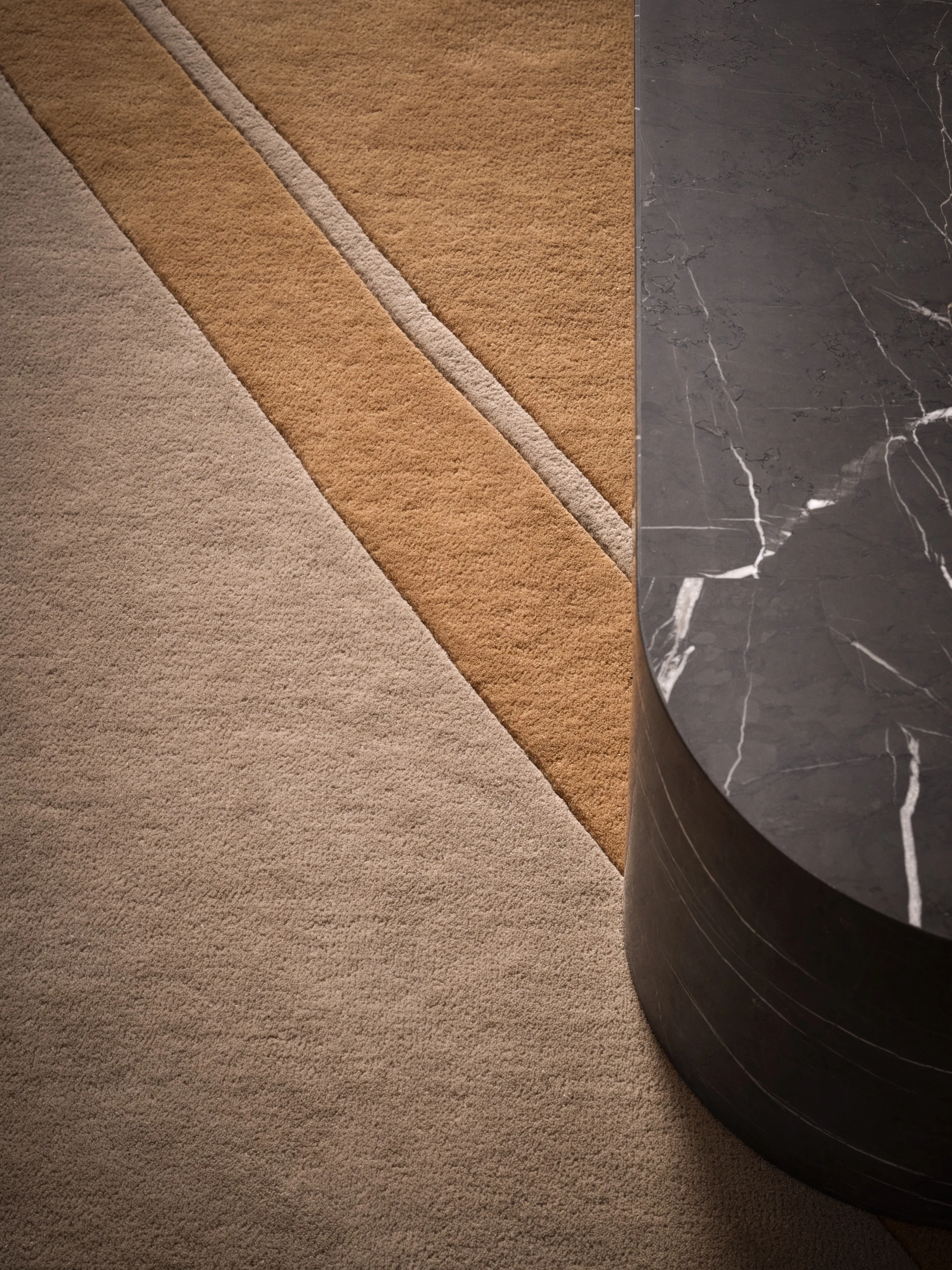 Sculpted wool rug curving around the base of a dark marble column