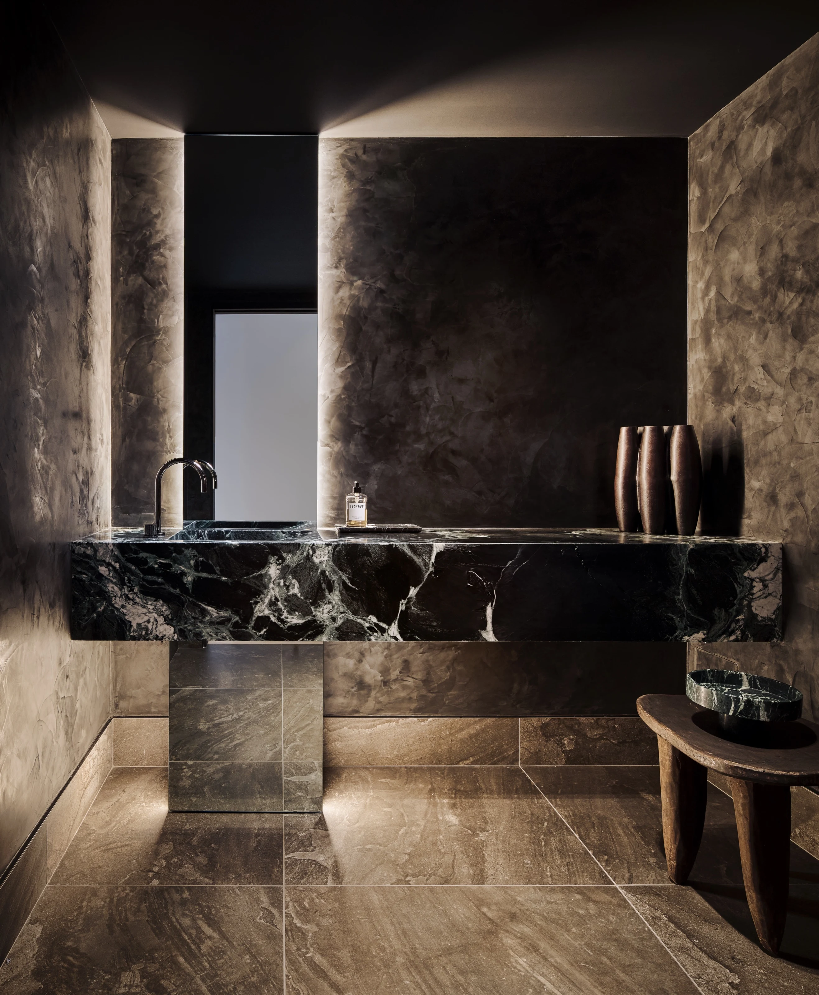 Verdi Alpi marble vanity in a dark stone powder room