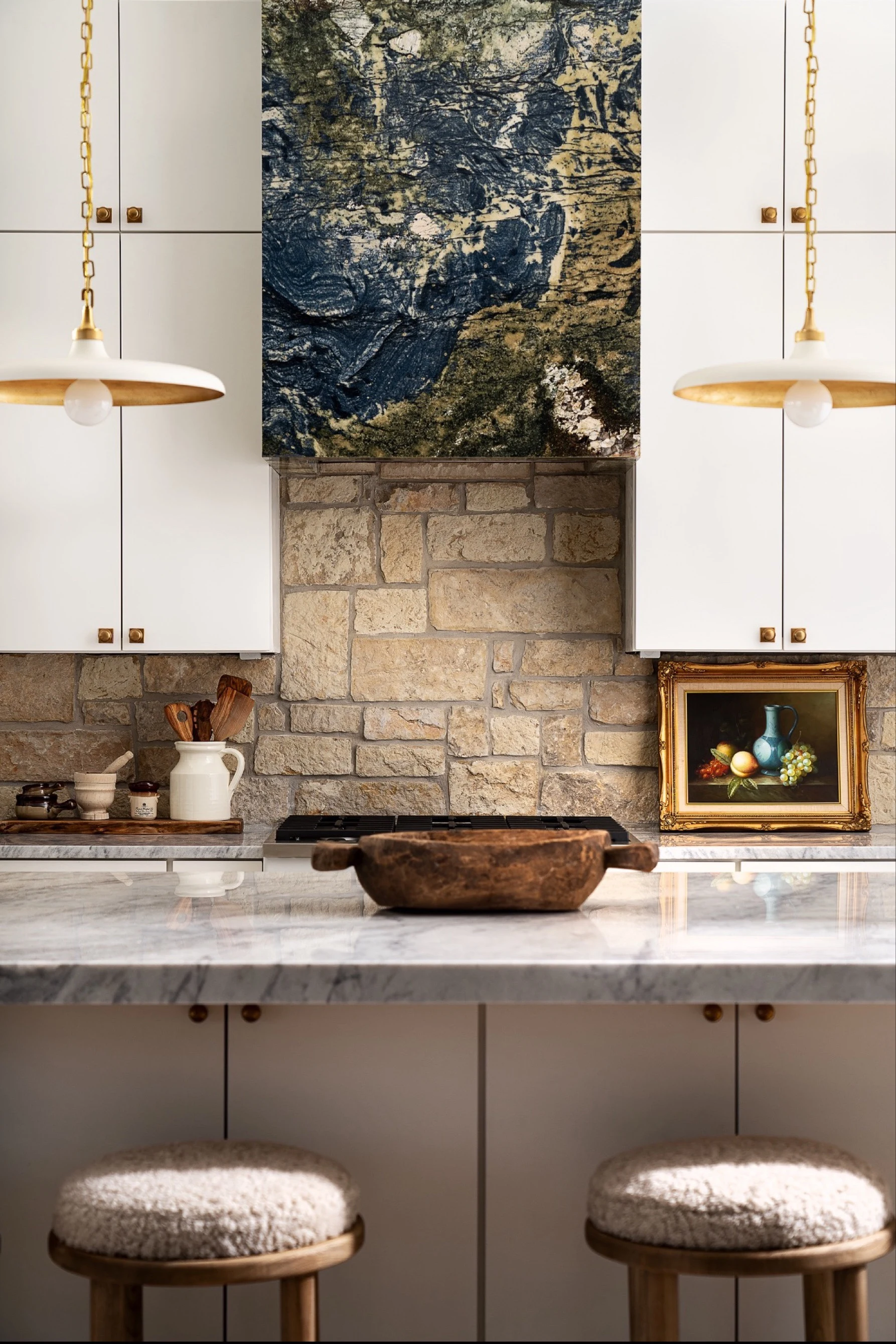 Avatar granite hood between white cabinets and brass-lined pendants