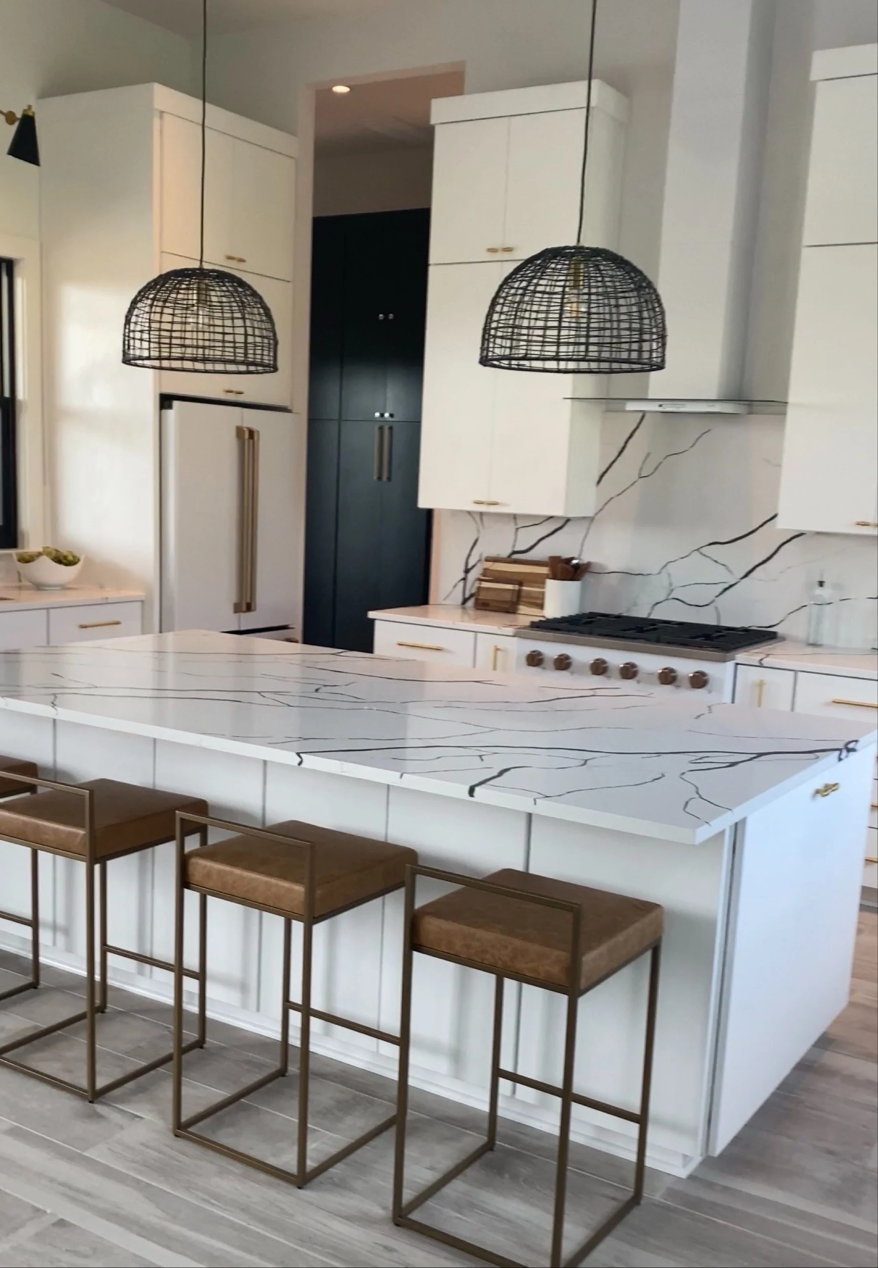 Kitchen before: white cabinetry, a veined backsplash and black wire pendants