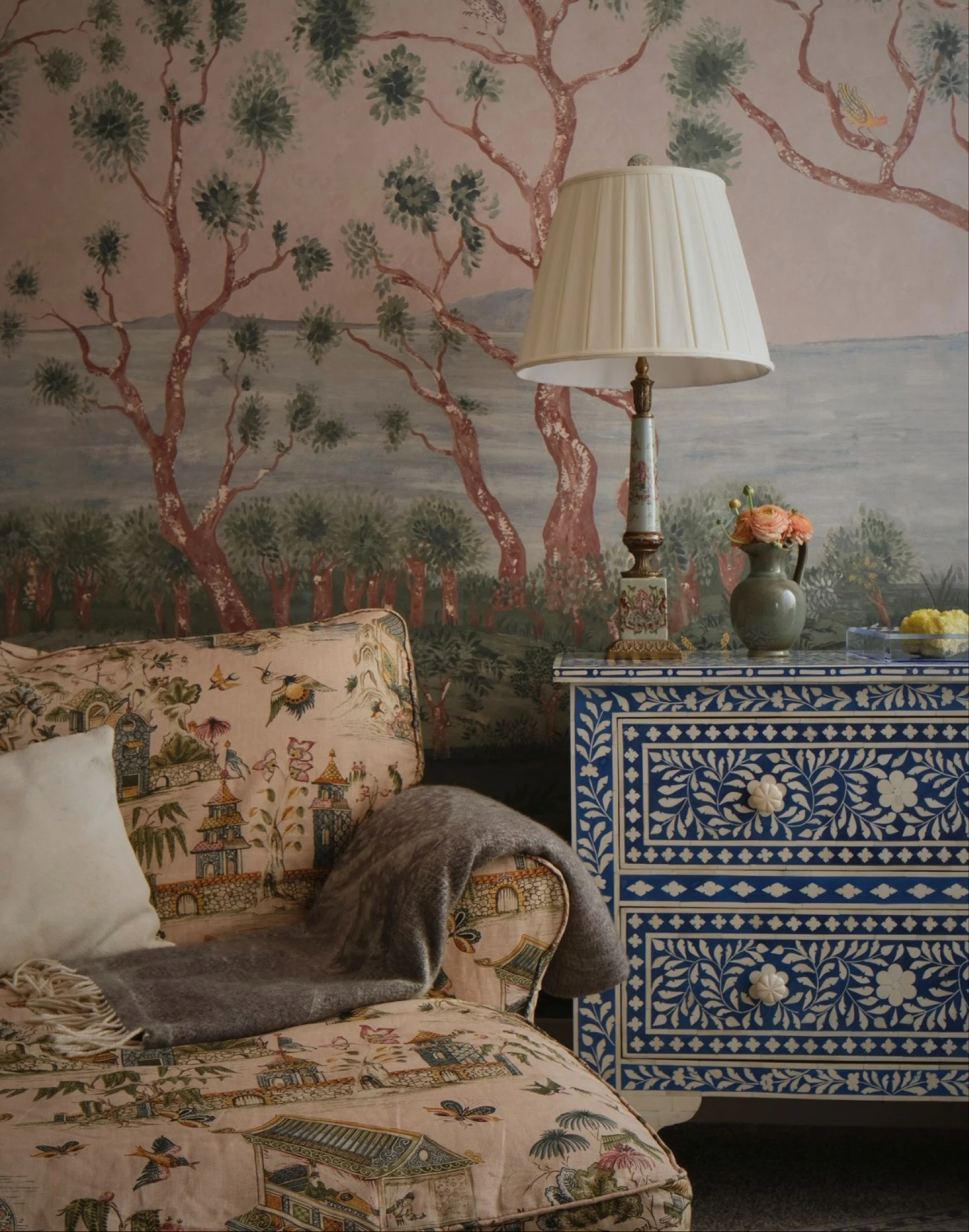 Chinoiserie sofa and bone-inlay chest before a hand-painted tree mural