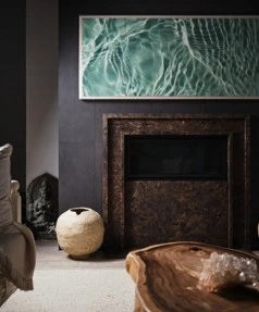 Dark stone fireplace surround beneath a sea-green painting