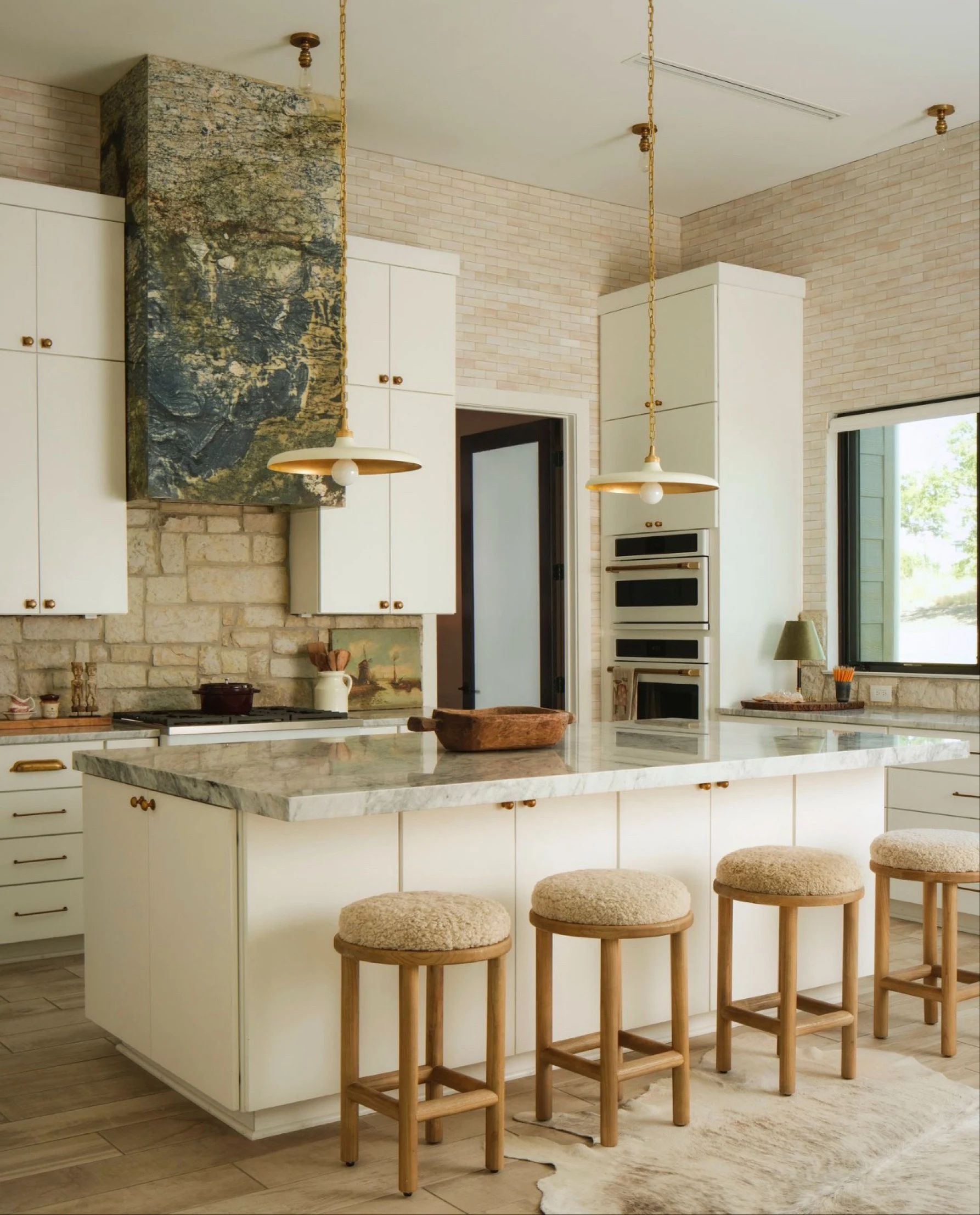 Kitchen with a blue-green Avatar granite hood, limestone backsplash and shearling stools at the island