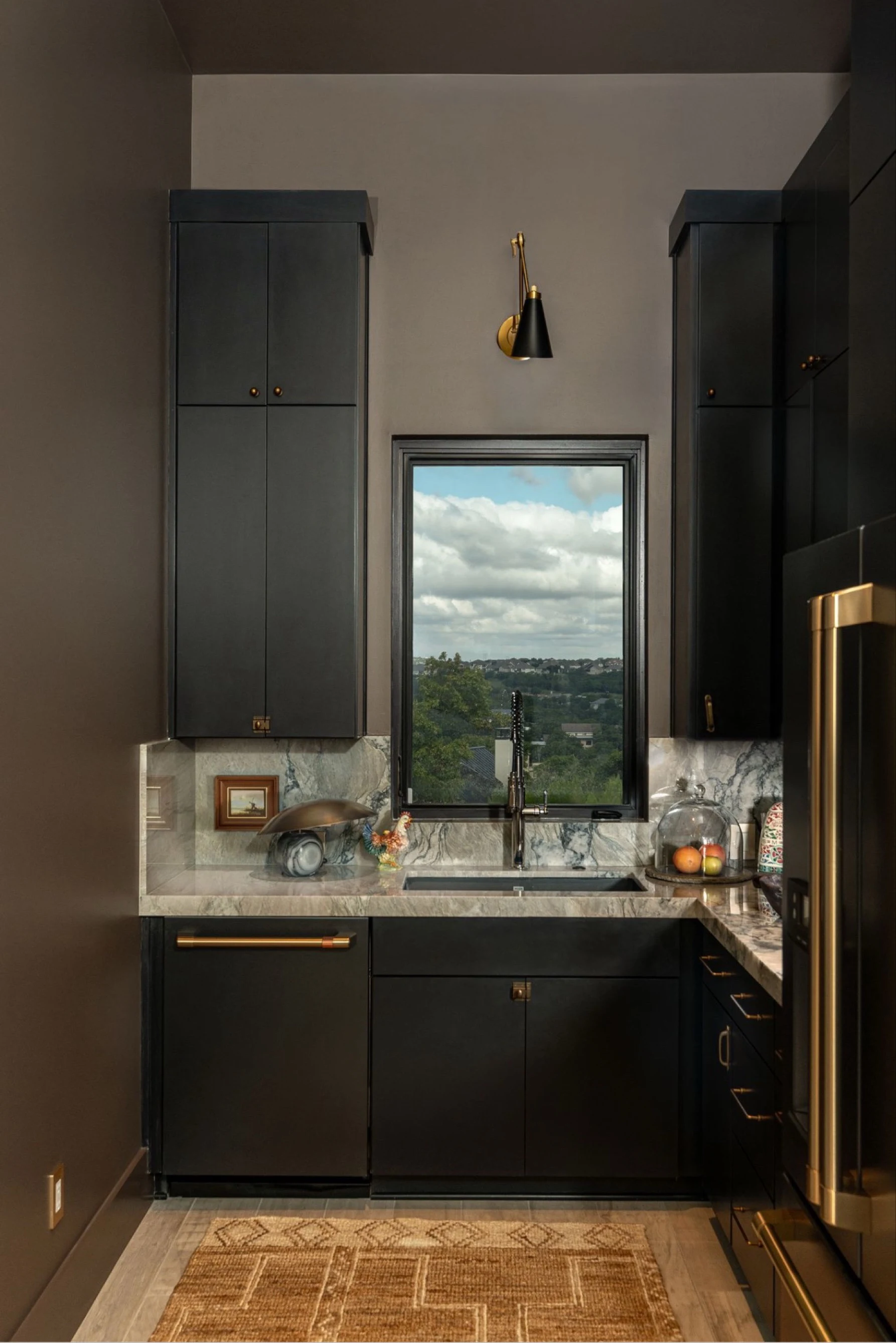 Butler's pantry with black cabinetry, a window over the sink and a woven runner