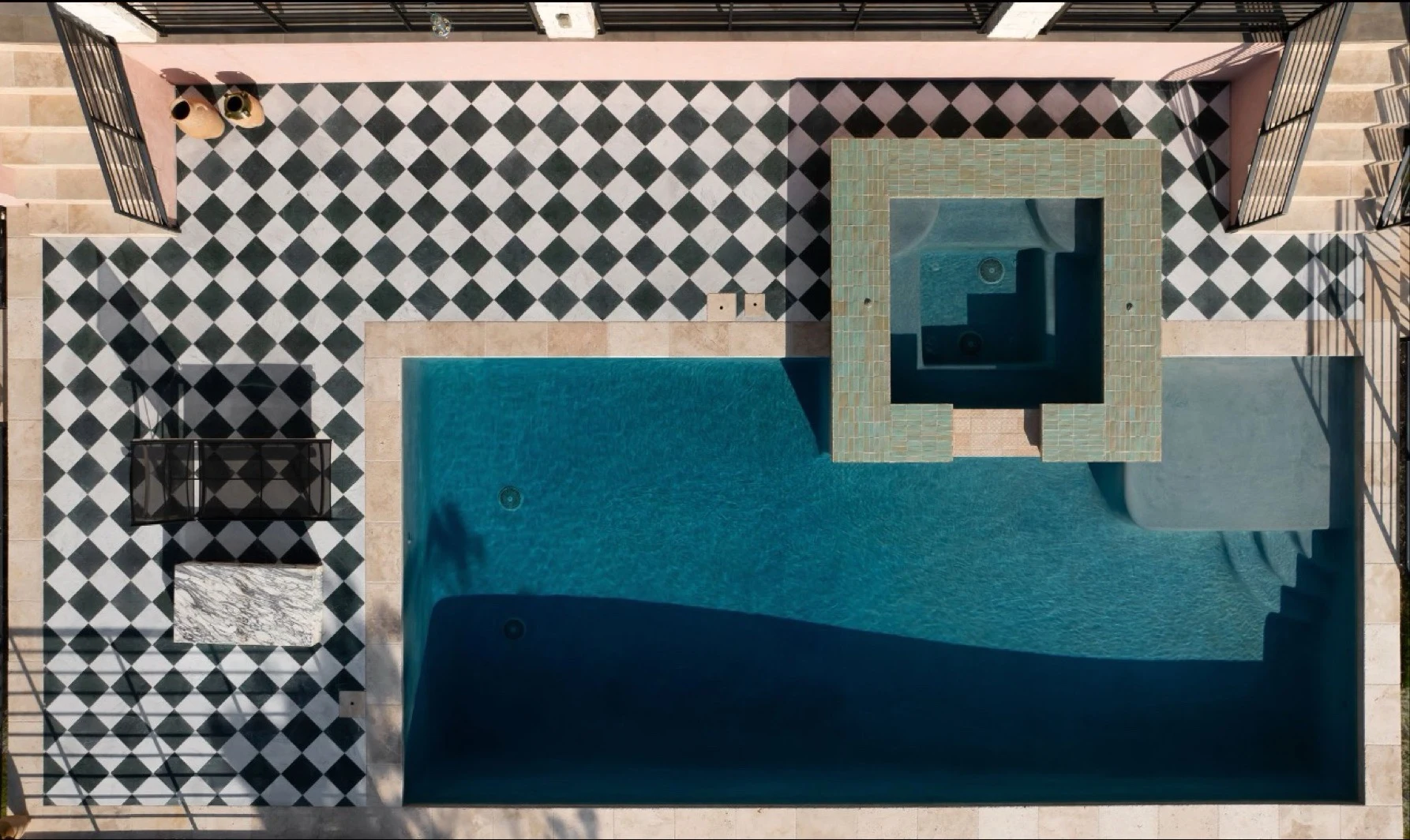 Aerial view of the pool and spa set in black and white checkerboard paving