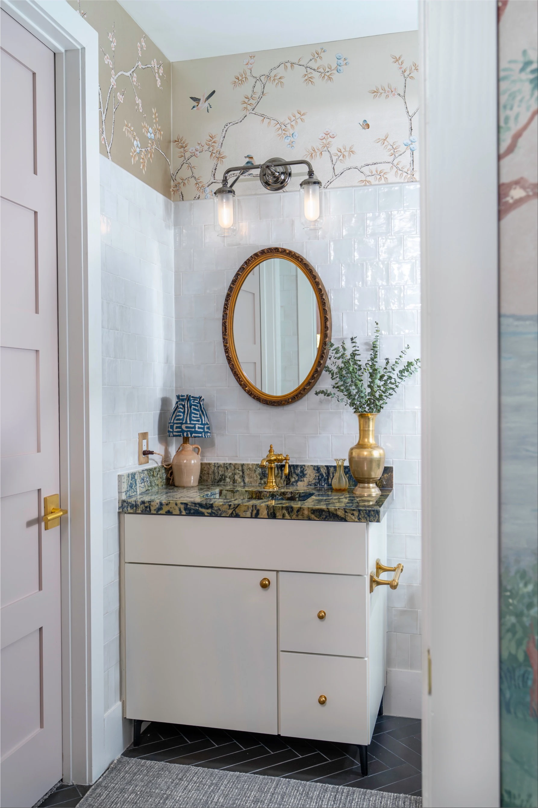 Powder room with an oval gilt mirror, chinoiserie wallpaper and a blue-green granite vanity