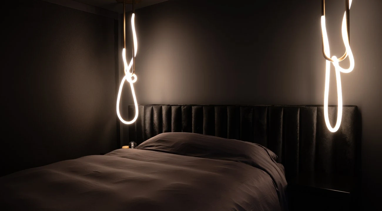 Looped neon pendants either side of the leather headboard