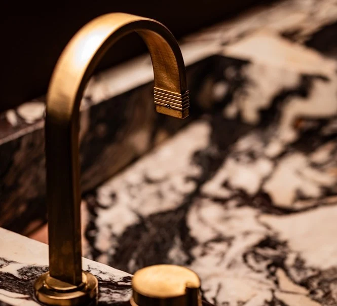 Aged brass faucet against the Calacatta Viola vanity