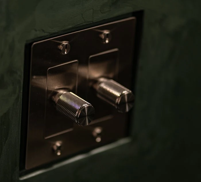 Brass shower valve set into the green stone wall