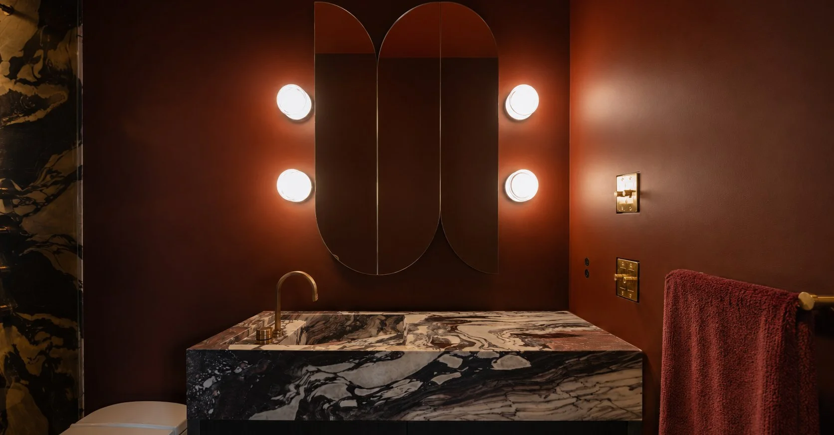 Calacatta Viola vanity and arched mirrors in an oxblood powder room