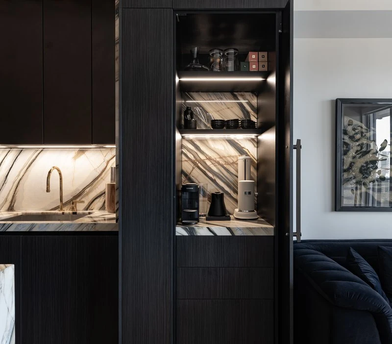 Blackened cabinetry and wall ovens beside the kitchen