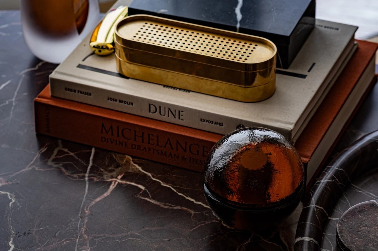 Brass box and stacked art books on a dark marble surface