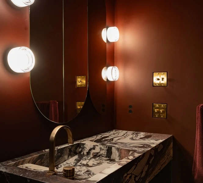 Round sconces and arched mirrors in the oxblood powder room