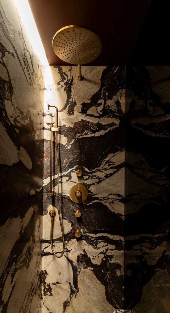 Brass shower fittings against book-matched Calacatta Viola