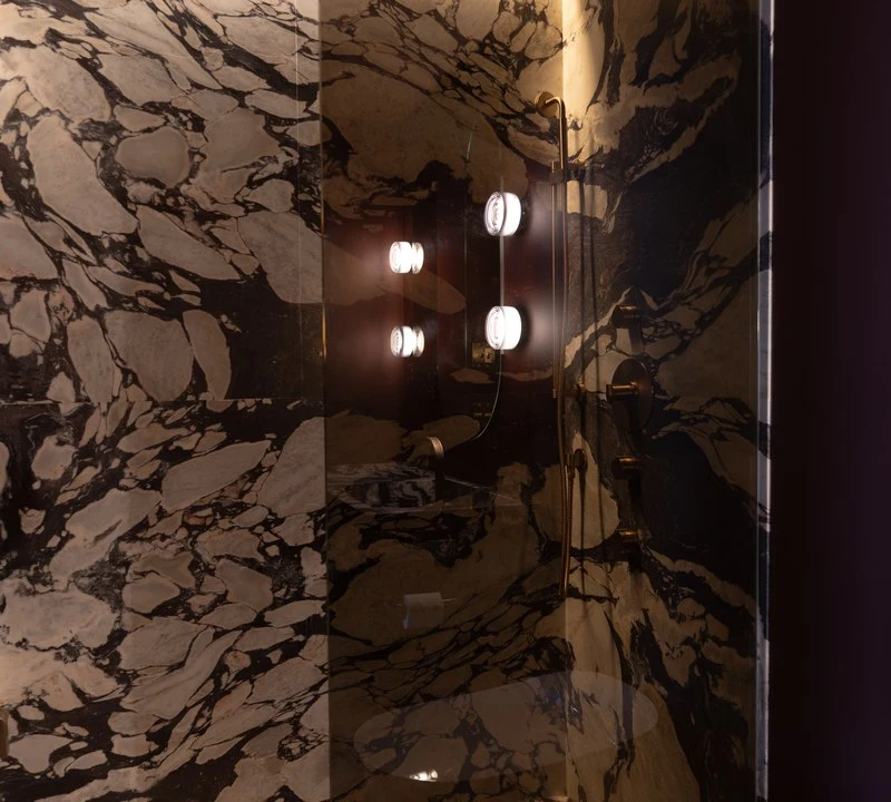 Sconces reflected in the Calacatta Viola shower wall