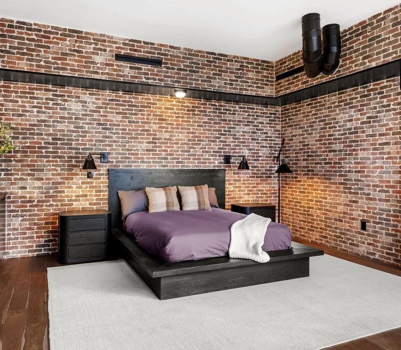 The bedroom seen across the rug toward the brick wall