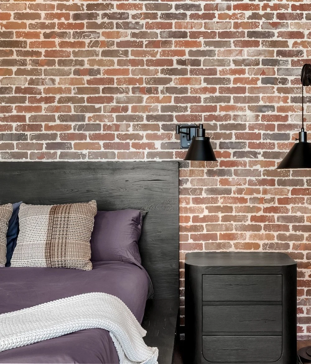 Exposed brick wall behind the bed in the primary bedroom