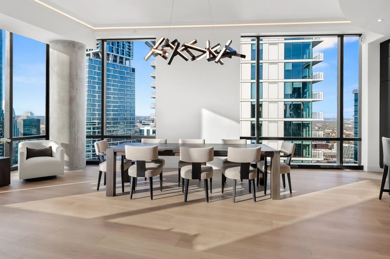 Dining table set against floor-to-ceiling skyline windows