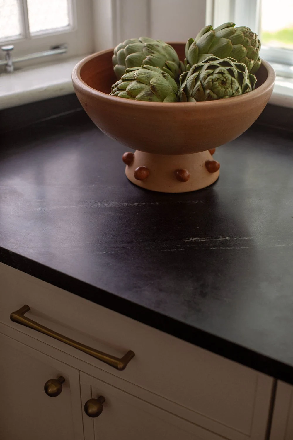 Terracotta bowl of artichokes on a honed soapstone counter