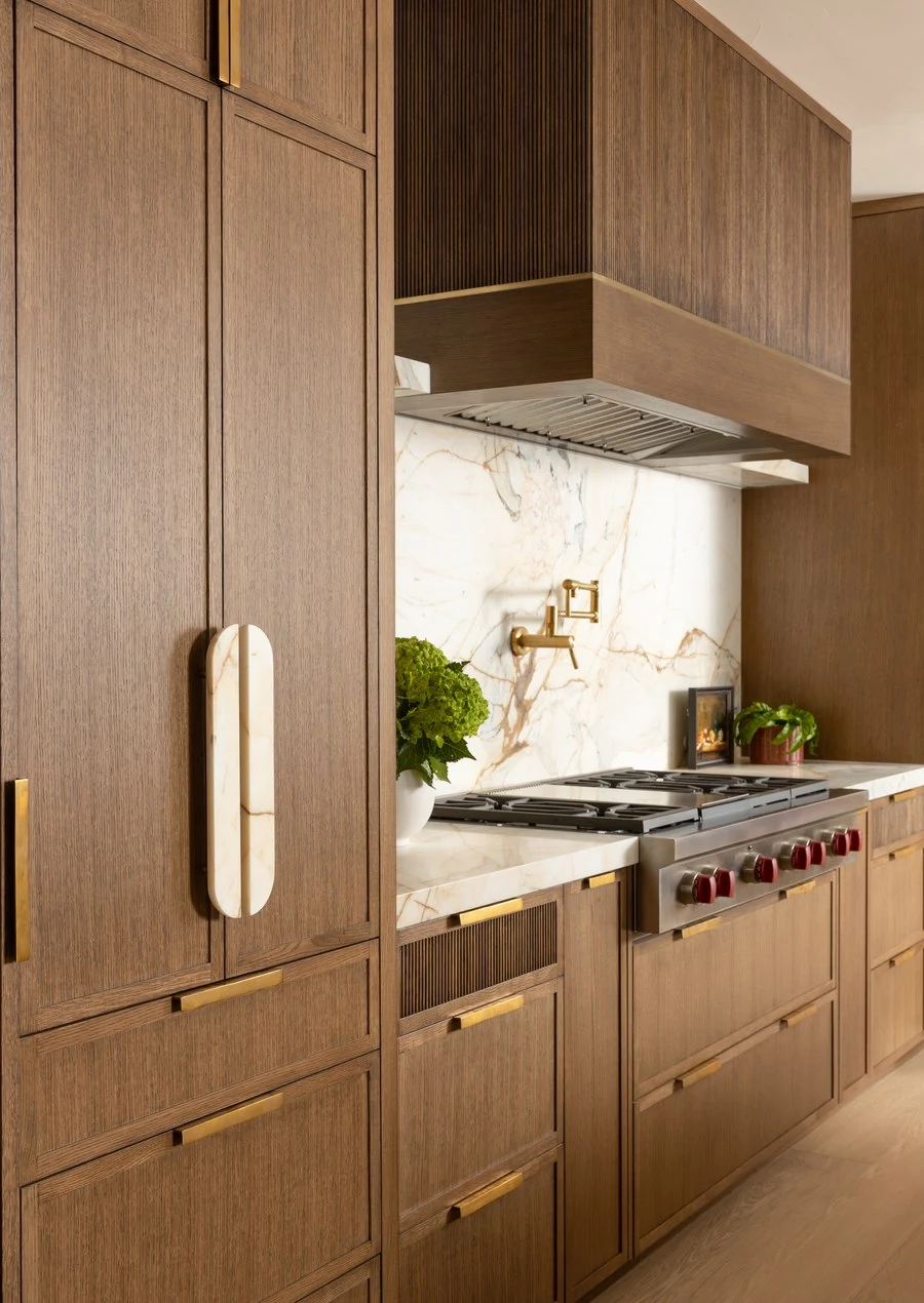 Walnut kitchen cabinetry with a slim vertical pull beside the range